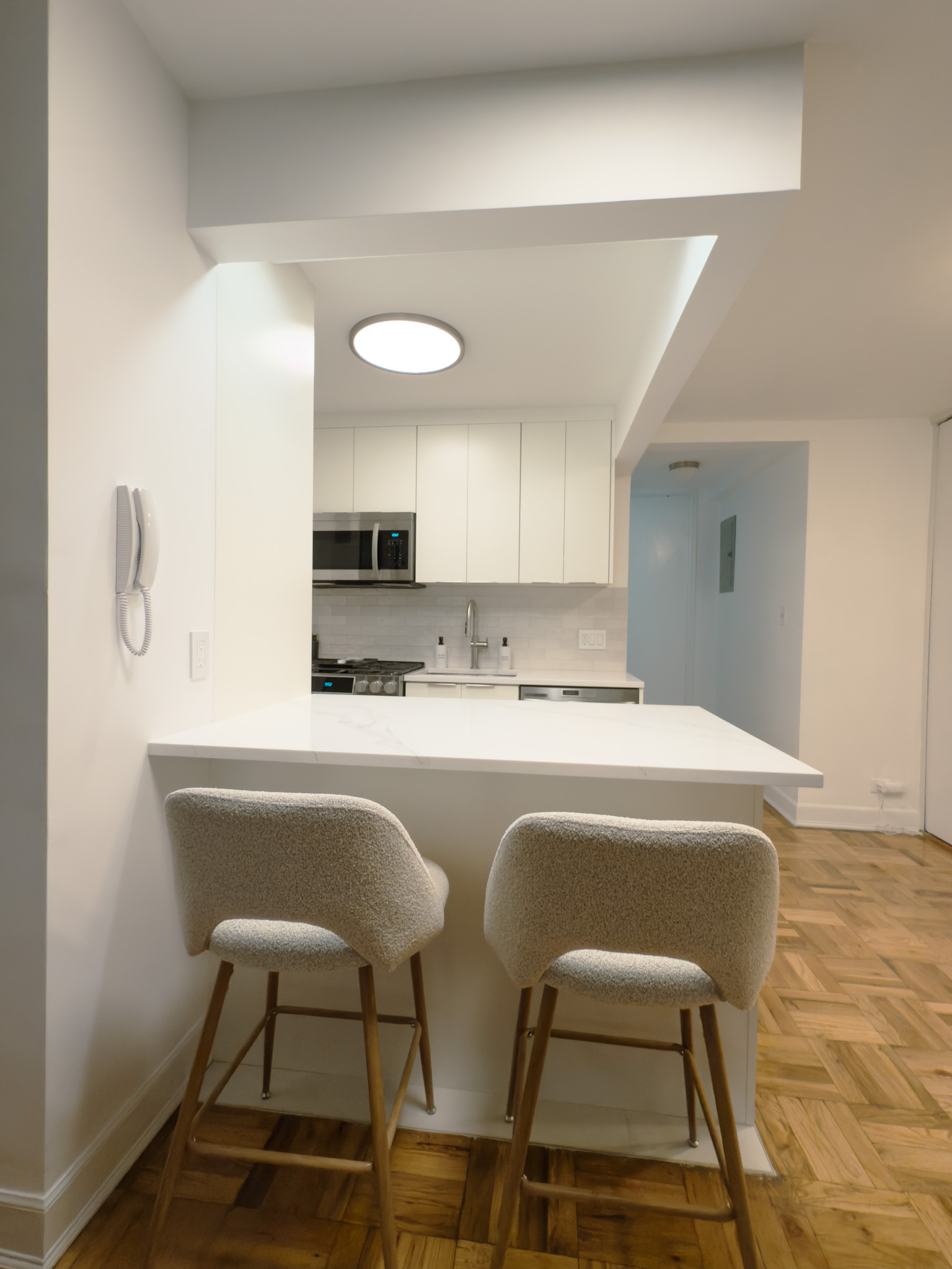 Peninsula bar with boucle stools and parquet hardwood floor